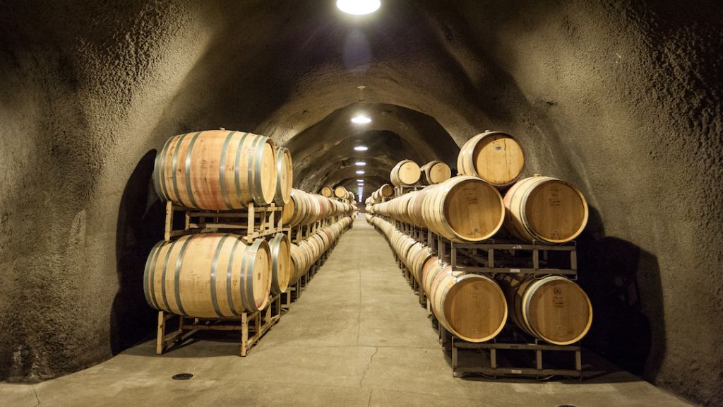 Wine barrels line an underground tunnel.