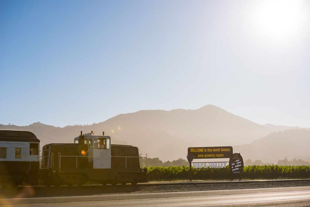 The Napa Valley Wine Train passes by a Welcome to Napa Valley sign.