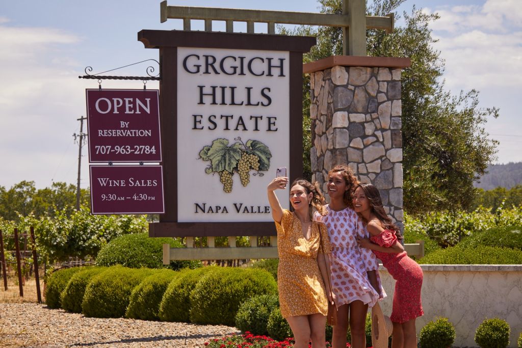 Three women pose in front of the Grgich Hills Estates sign