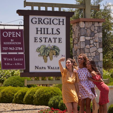 Three women pose in front of the Grgich Hills Estates sign