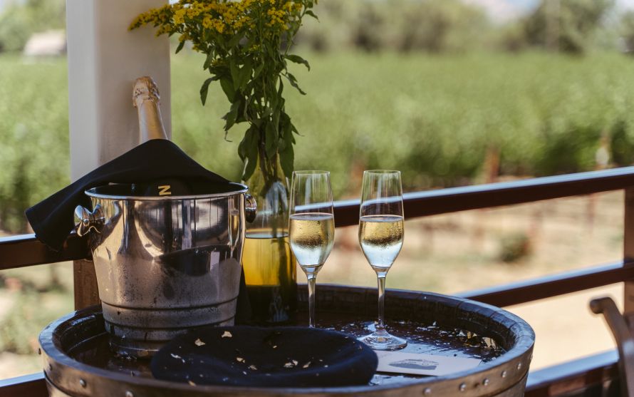 Champagne in an ice bucket with two flutes of champagne beside it.
