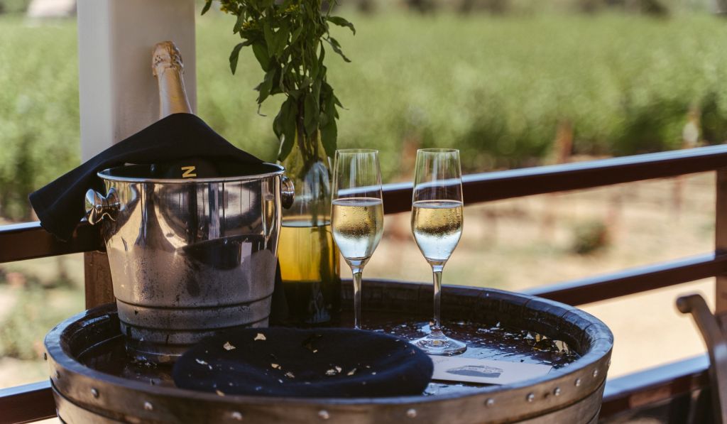 Champagne in an ice bucket with two flutes of champagne beside it.