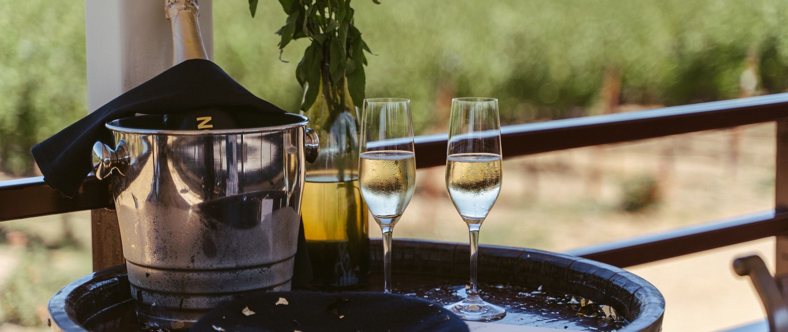 Champagne in an ice bucket with two flutes of champagne beside it.