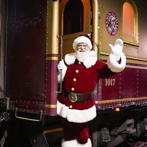 Santa Klaus waving as he stands on the Wine Train