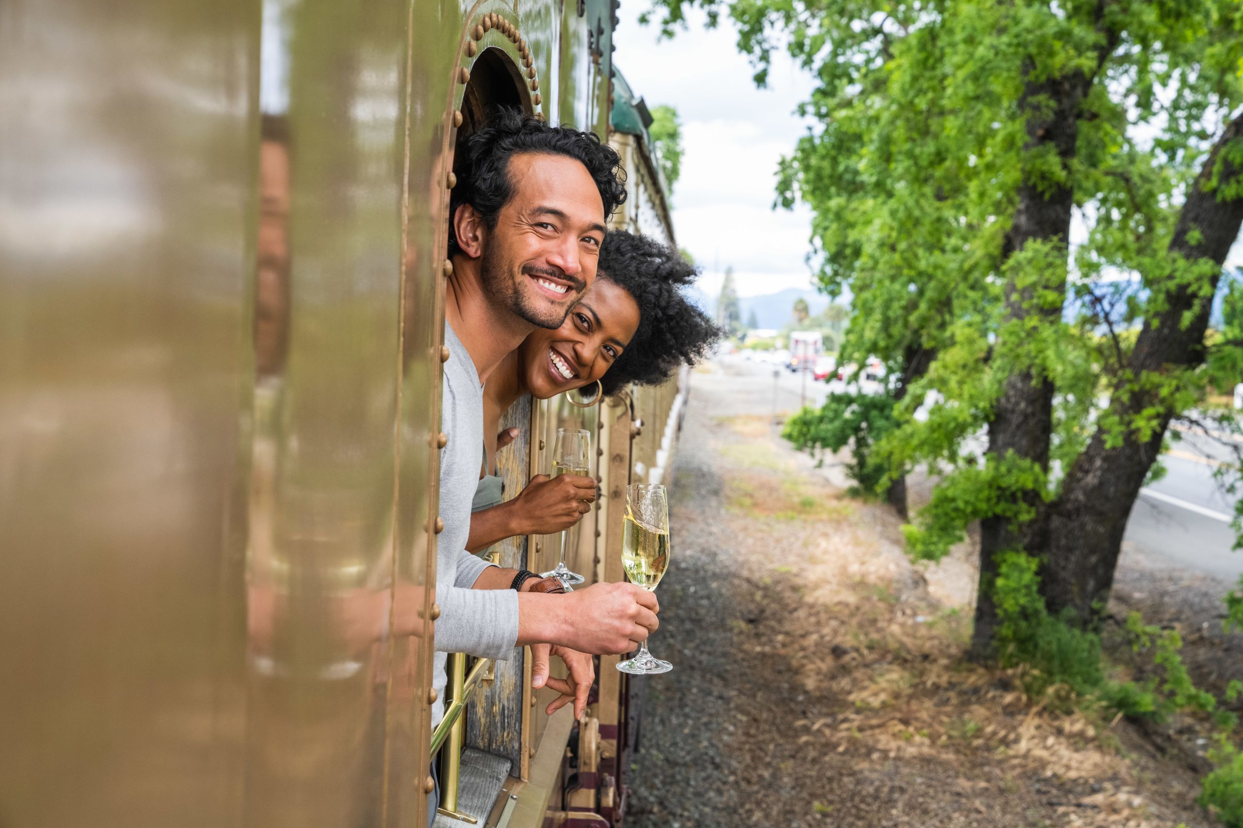Couple hangs out of window with wine glasses