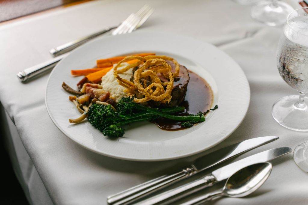 Professionally plated Steak, mashed potatoes, broccoli, crisp onions, and carrots