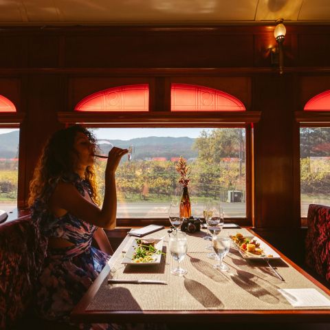 Woman drinking from her wine glass, sat in an elegant red booth