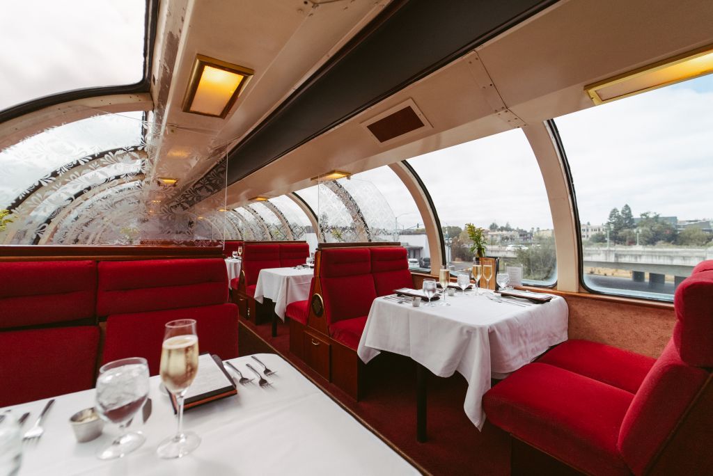 Dining car with detailed stain glass dividers contrasted by velvet red seats