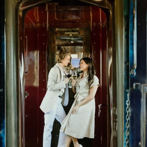Two adults toasting their wine glasses as they gaze lovingly at one another