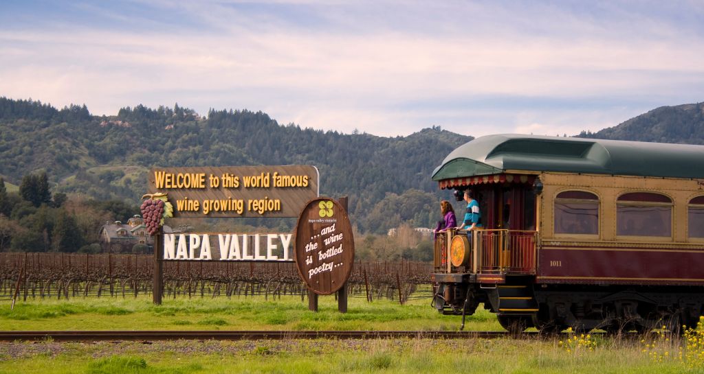 Two guests look at the Welcome to Napa Valley sign from onboard the Wine Train