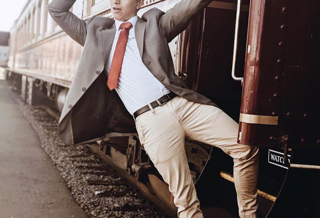 Man hanging from train tipping his hat