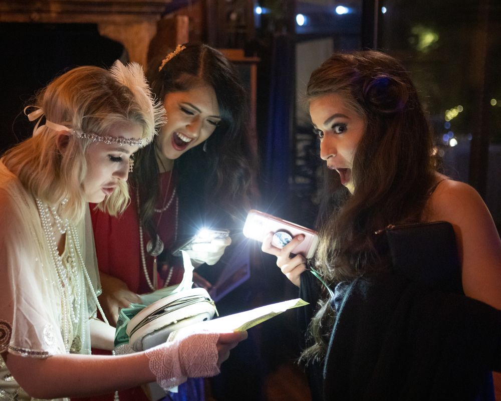 Three women review their clues during murder mystery dinner
