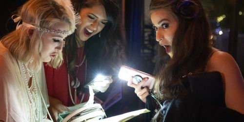 Three women review their clues during murder mystery dinner