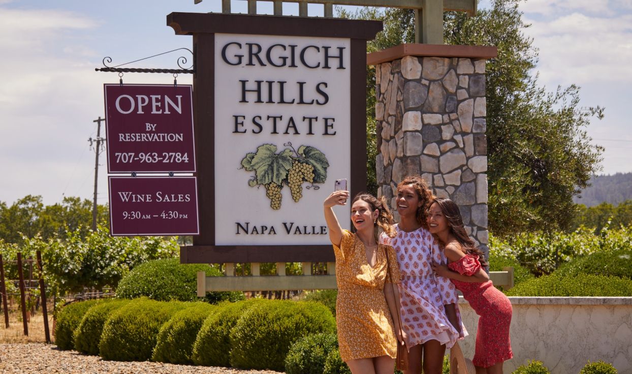 Three women pose in front of the Grgich Hills Estates sign