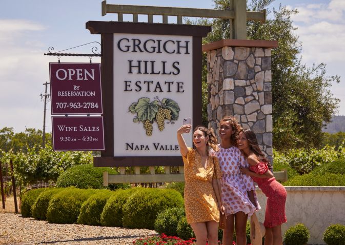 Three women pose in front of the Grgich Hills Estates sign