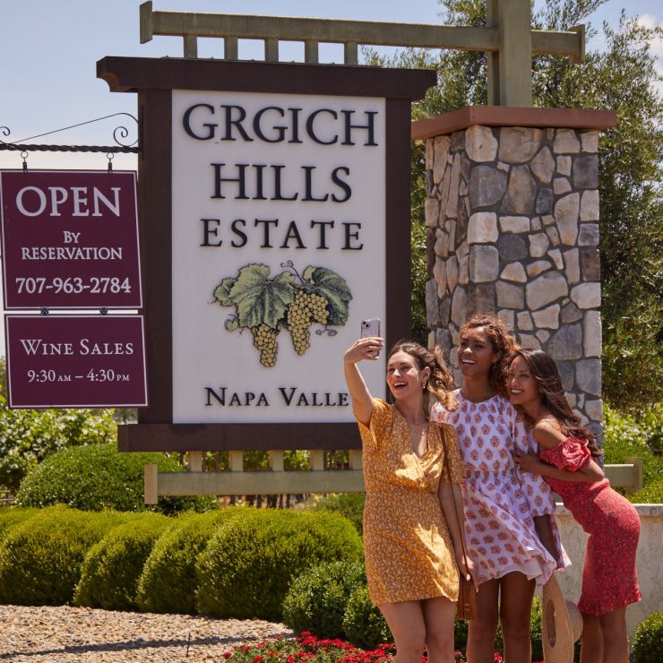 Three women pose in front of the Grgich Hills Estates sign