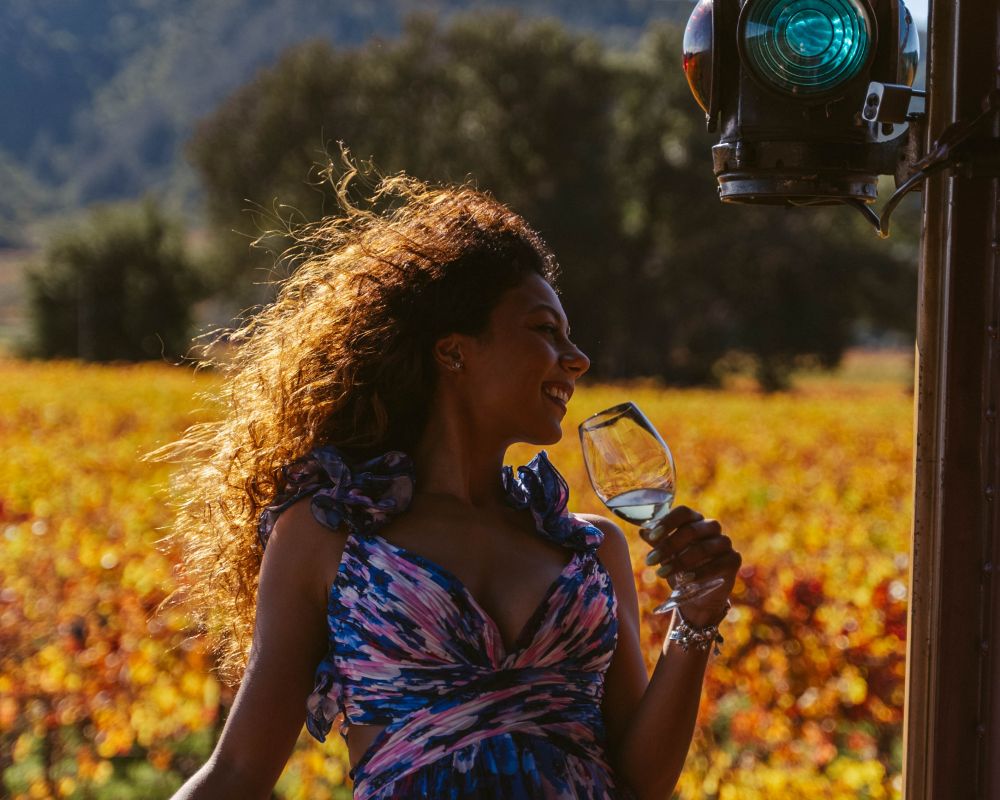 A woman leaned back looks to the right while holding a wine glass