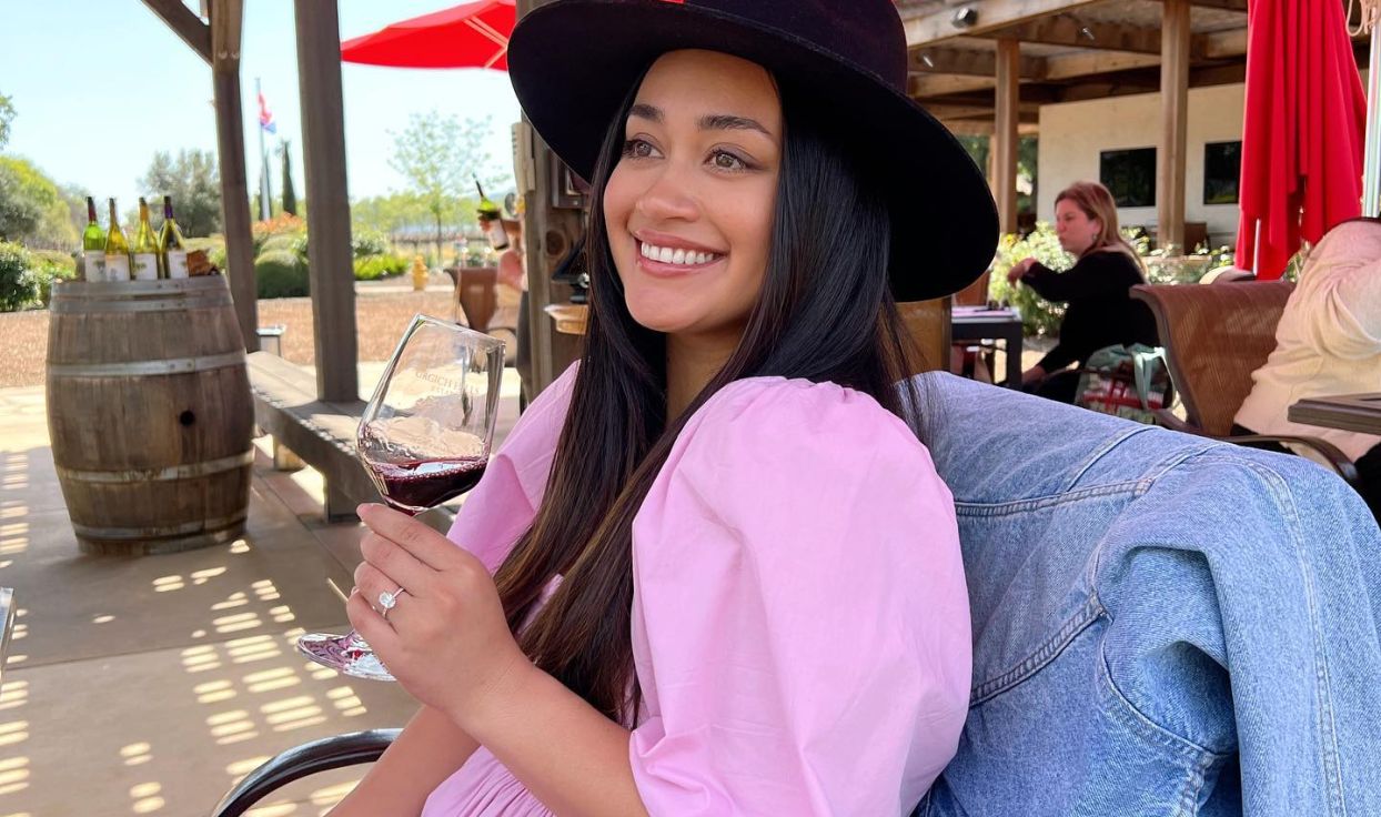 Woman in pink dress poses with glass of red wine