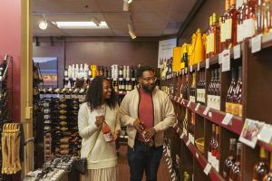 Two adults hold bottles of wine while perusing the Wine Train shop