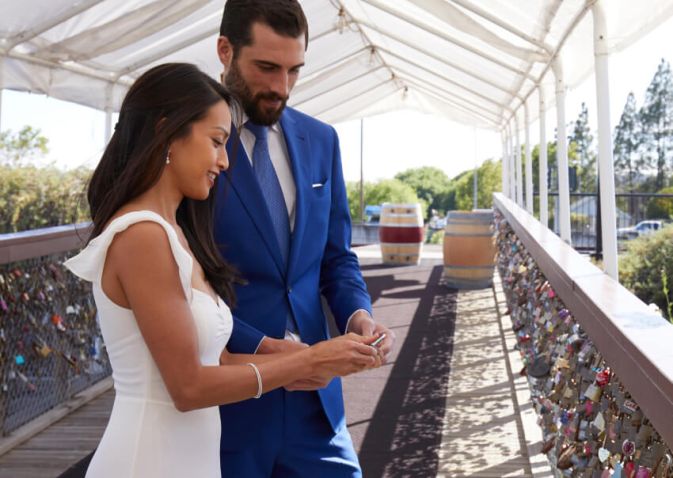 Bride and groom decide where to play their lock on the chain link fence