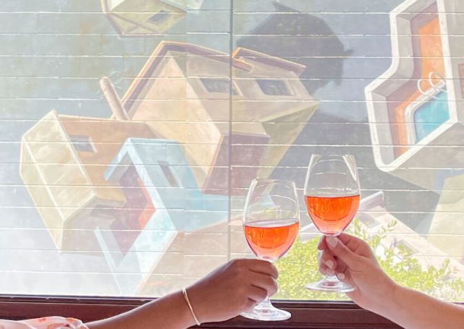 Couple clinks wine in front of a mural