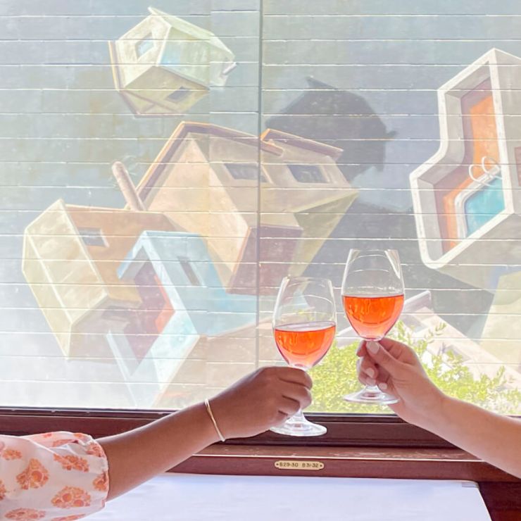 Couple clinks wine in front of a mural