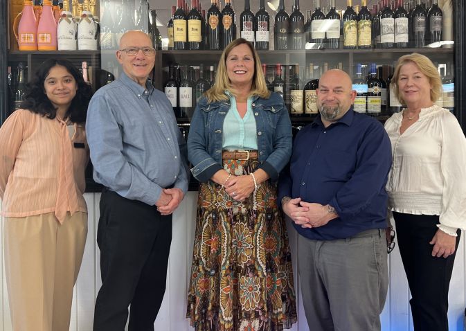 Five adults posing for photo at the wine store and gift shop