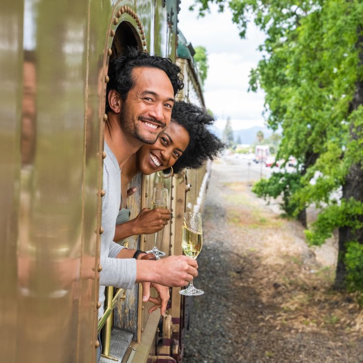 Couple hangs out of window with wine glasses