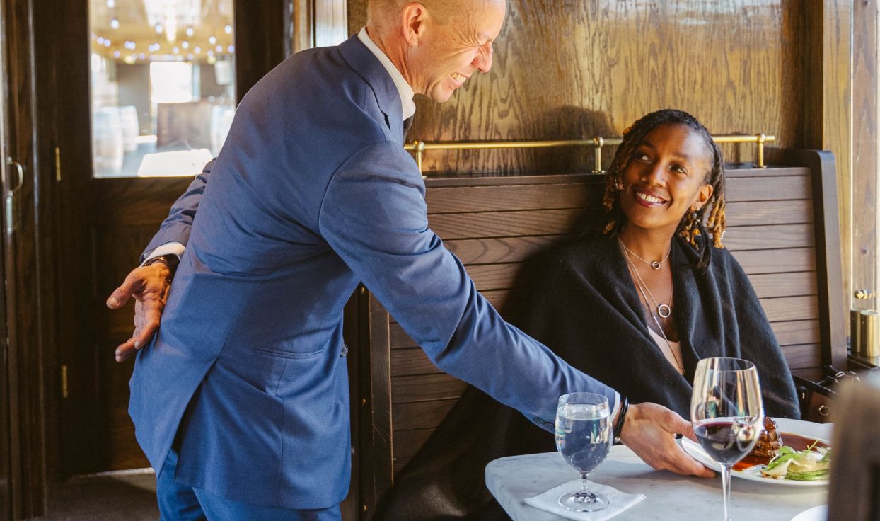 Server takes a finished dinner plate from table