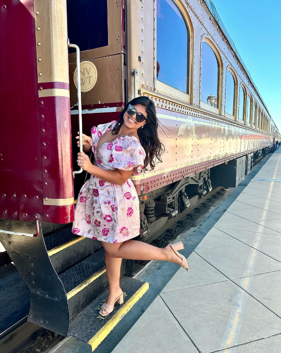 A woman poses as she hangs from the Wine Train step
