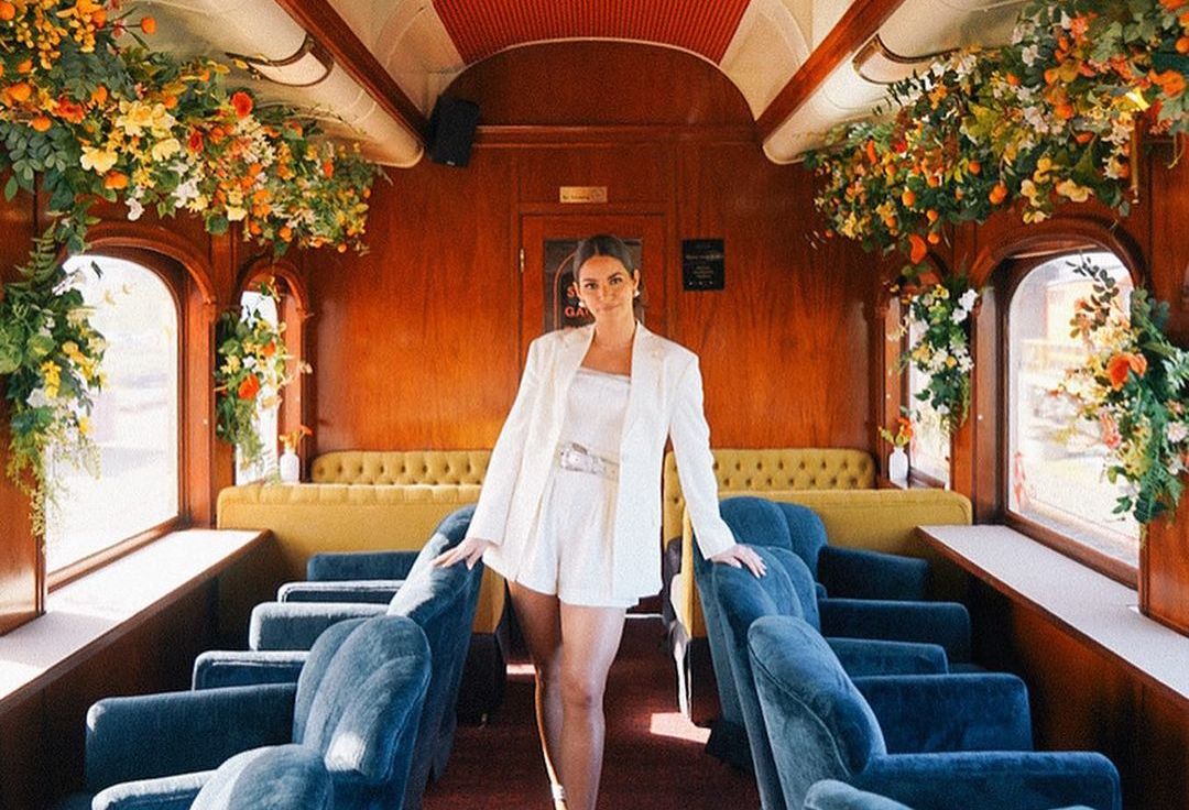Woman in white poses in the middle row of the Wine Train car
