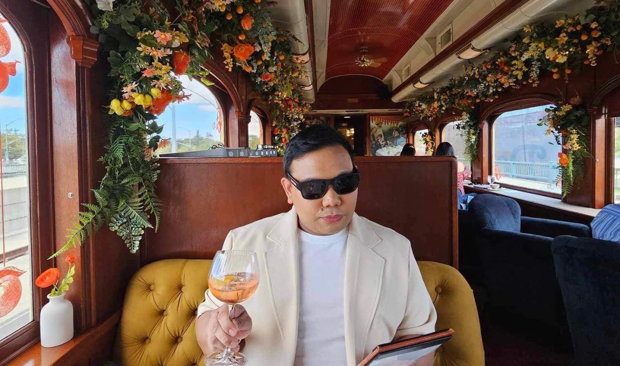 Man poses with wine glass and sunglasses